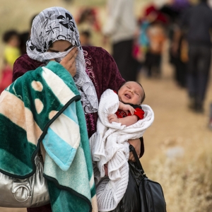 Mor er på flugt fra Syrien med sit barn på armen. Foto: UBS. 