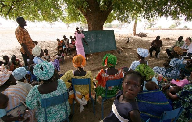 En gruppe mennesker modtager læseundervisning i skyggen i Tattaguine, Senegal. Foto Joaquim Dassonville / UBS. 